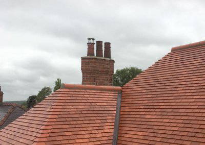 Completed red tiled roof with chimney stacks